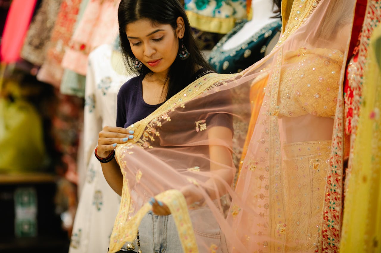 services-02 Young South Asian woman examining saree fabric while shopping indoors.